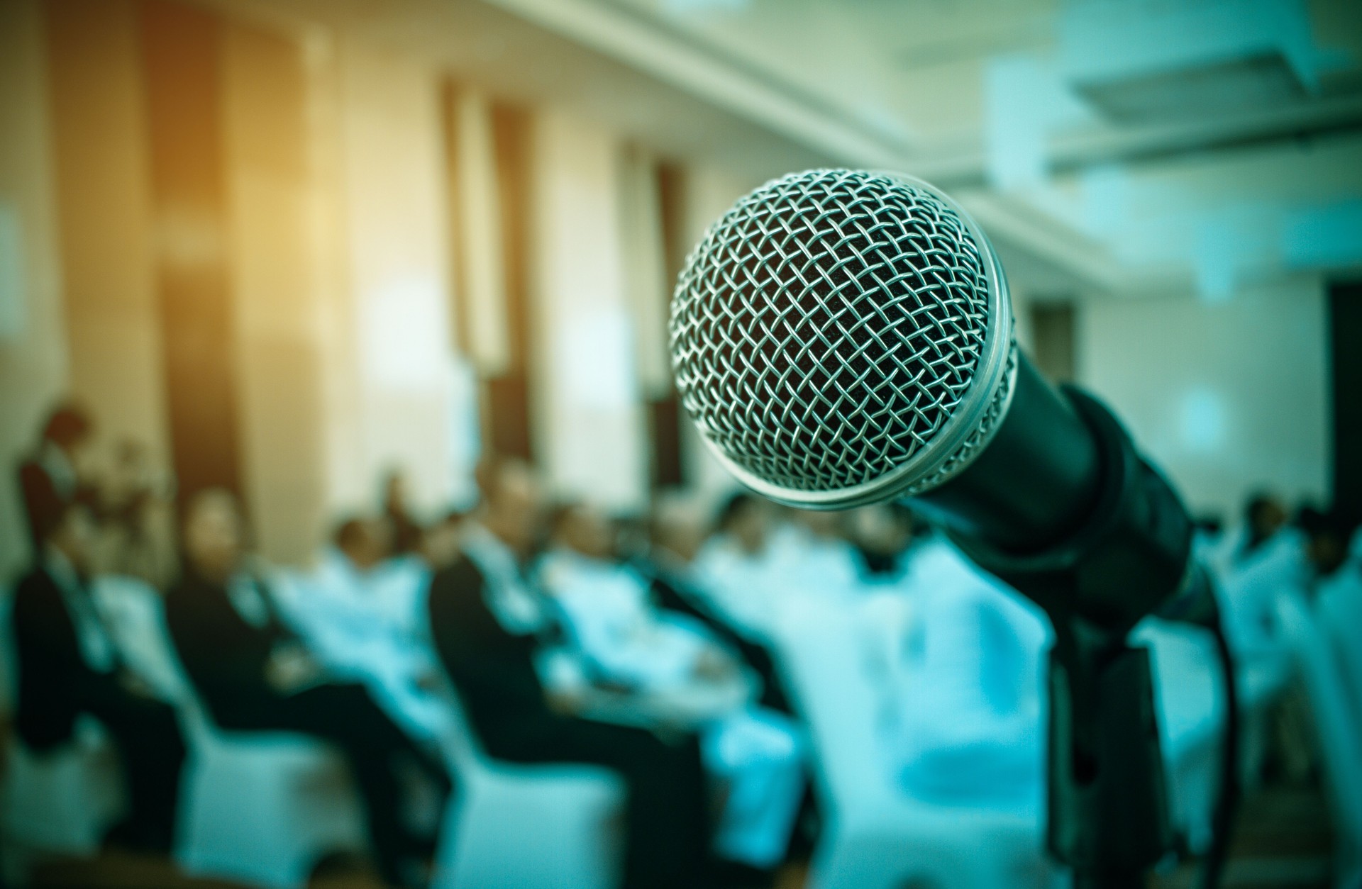 Audience listening speaker speech in conference hall or seminar room with blur light people background. Seminar is form of academic instruction, offered by commercial or professional organization.