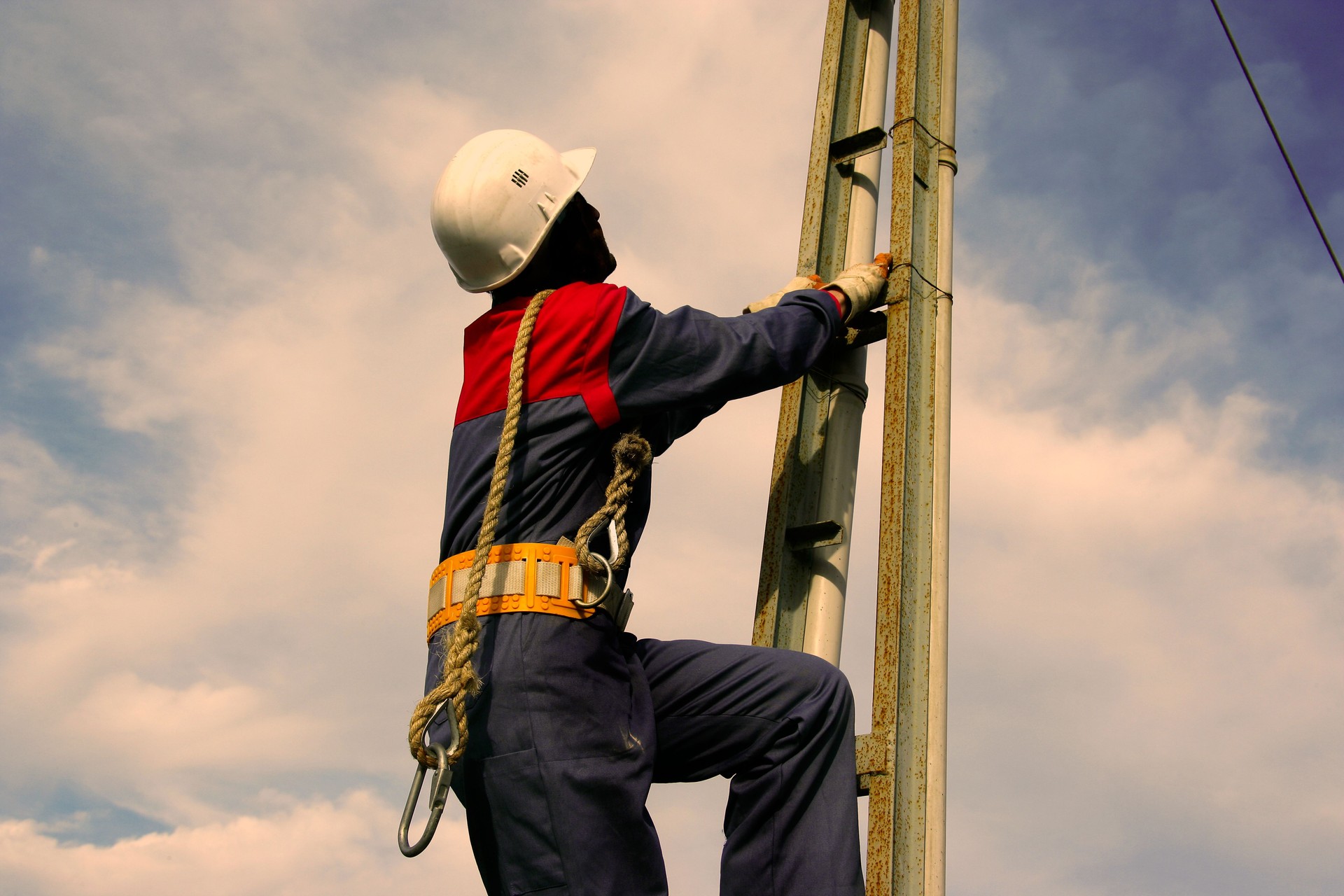 Electrician climbing power line pole